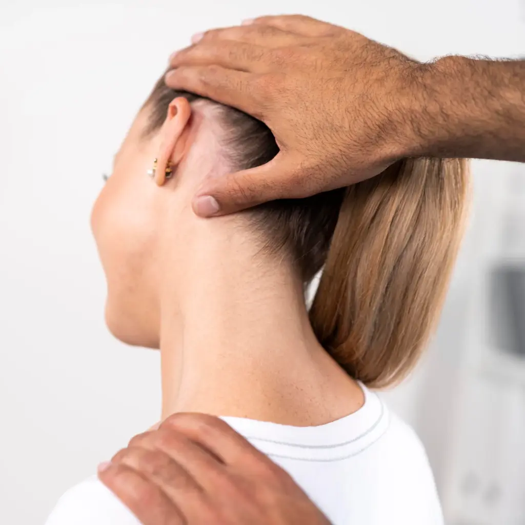 Practitioner's hands supporting a woman's head and shoulder during a neck adjustment