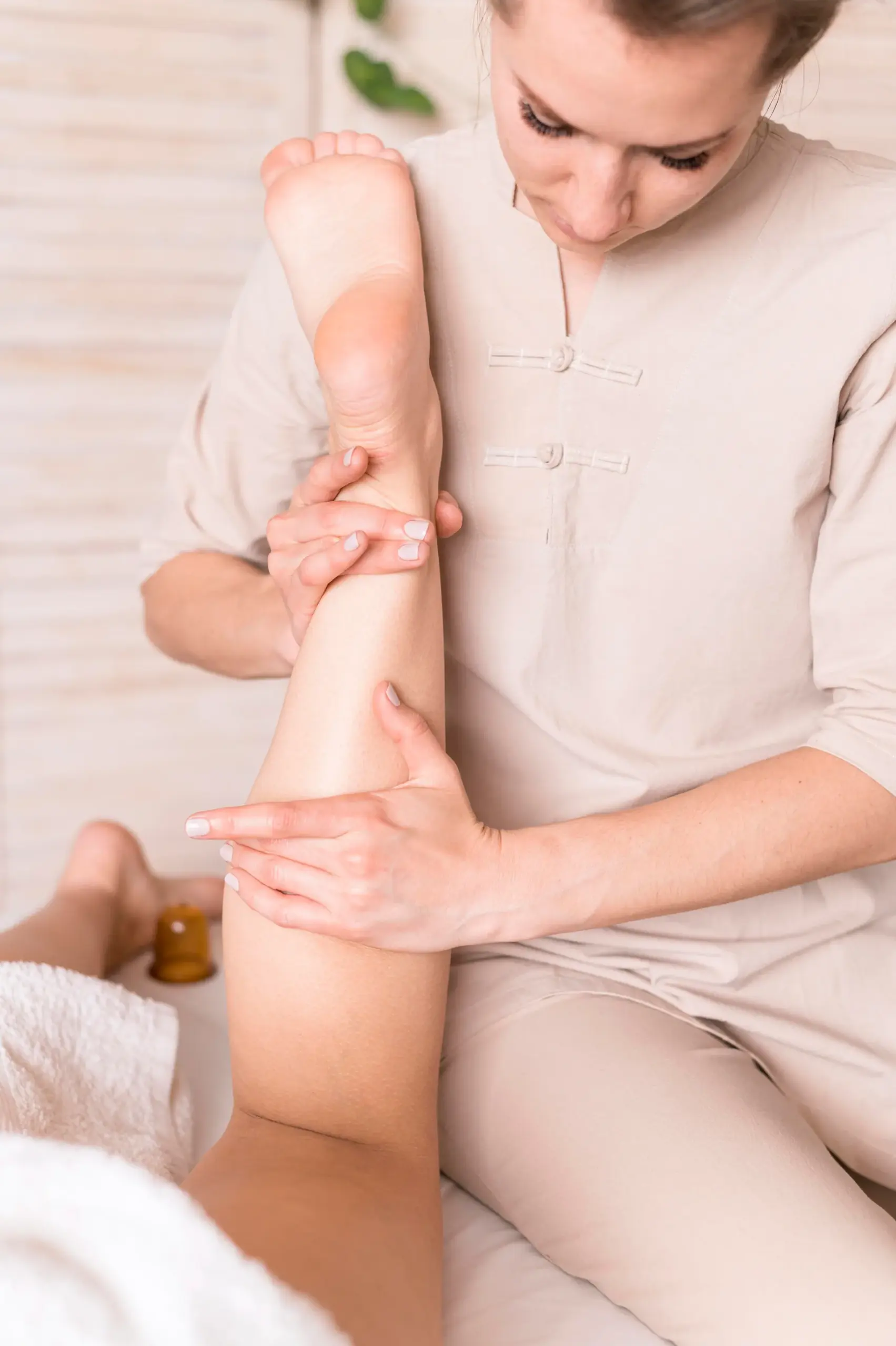 Close-up of a massage therapist supporting a client's raised leg while massaging the calf muscle.